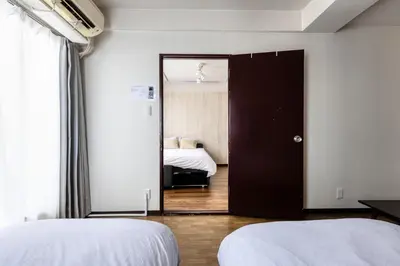 a bedroom with two beds and a door with a mirror at Shibuya Crossing 5mins walk COZY BRIGHT COMFY PAD 35sqm in Tokyo