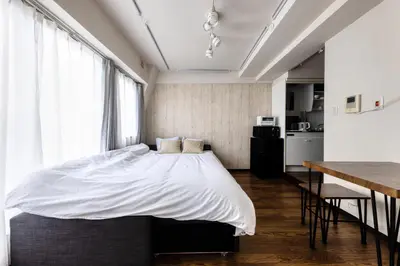 a bedroom with a bed and a table and a kitchen at Shibuya Crossing 5mins walk COZY BRIGHT COMFY PAD 35sqm in Tokyo
