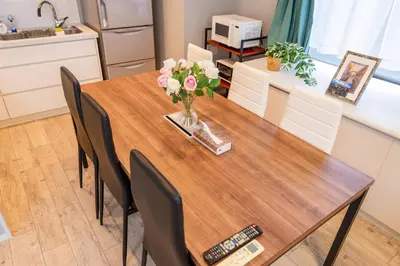 a dining room table with a vase of flowers on it at \u76ee\u767d Yoko hotel shinnjuku, shinokubo 10 people stay, big room in Tokyo