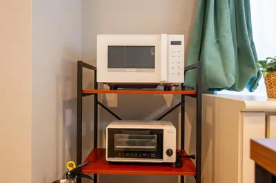 a microwave and a toaster oven on a shelf at \u76ee\u767d Yoko hotel shinnjuku, shinokubo 10 people stay, big room in Tokyo