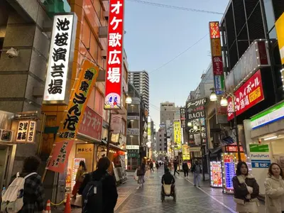 a busy city street with people walking down the street at The Hope Ikebukuro in Tokyo