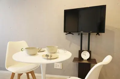 a white table with two chairs and a tv on a wall at Heureux\u690e\u540d\u753a301 in Tokyo