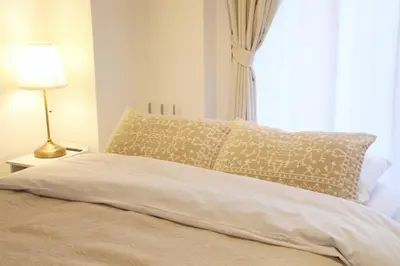 a bed with a pillow and a lamp next to a window at \u30ac\u30a4\u30a2\u6b4c\u821e\u4f0e\u753a203 in Tokyo