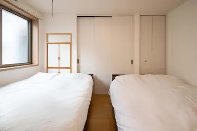 two white beds in a room with a window at Elle Maison\u5927\u68ee 102 in Tokyo