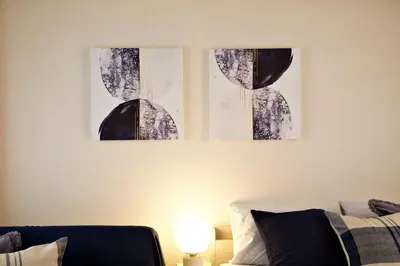 two paintings hanging on a wall above a couch at \u30b5\u30f3\u30cf\u30a4\u30c4\u521d\u53f0401 in Tokyo