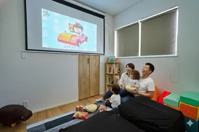a family sitting on a couch watching a presentation on a screen at Birthday House Skytree in Tokyo