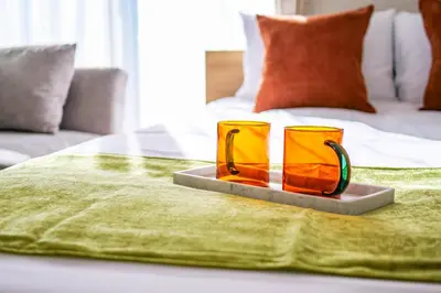 two orange glasses sitting on a tray on a bed at Mr Kintaro Hotel Kinshicho in Tokyo