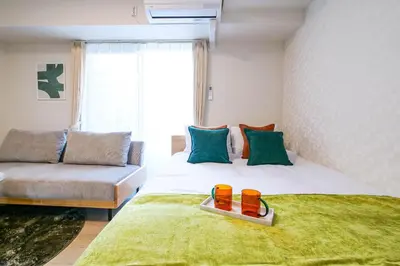 a bedroom with a bed with a couch and a large window at Mr Kintaro Hotel Kinshicho in Tokyo