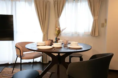 a dining room table with plates and chairs in front of a window at studio aoi 302 in Tokyo