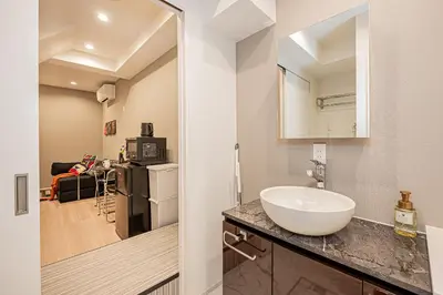 a bathroom with a sink and a kitchen with a refrigerator at Mi-HOTEL SHIMOKITAZAWA in Tokyo