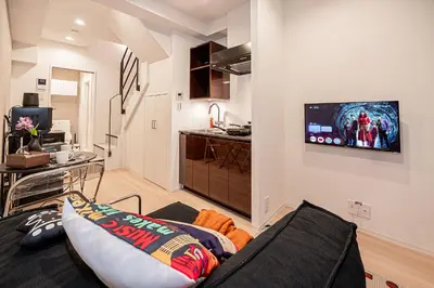 a living room with a couch and a tv on a wall at Mi-HOTEL SHIMOKITAZAWA in Tokyo