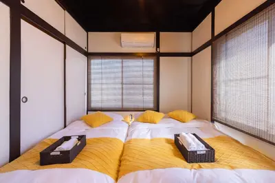 a bedroom with two beds with yellow pillows at Tokyo Disneyland\u8eca20\u5206 Shinjuku Akihabara\u96fb\u8eca\u76f4\u901a\u306e\u5927\u6b63\u98a8\u8cb8\u5207\u4e00\u8ed2\u5bb6 in Tokyo