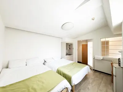 two beds in a room with white walls at \u82b1\u4e43\u90f7\u6c60\u888b4\u4e01\u76ee in Tokyo