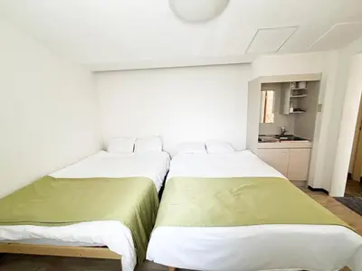 two beds in a white room with a kitchen at \u82b1\u4e43\u90f7\u6c60\u888b4\u4e01\u76ee in Tokyo