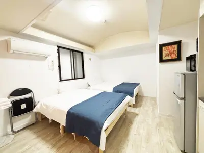 two beds in a small room with a window at \u82b1\u4e43\u90f7\u6c60\u888b4\u4e01\u76ee in Tokyo