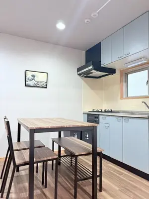 a kitchen with a wooden table and chairs in a room at GARDEN HOUSE Shinjuku-Sanchome in Tokyo