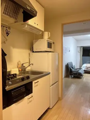 a kitchen with a white refrigerator and a sink at \u30a2\u30eb\u30b9\u30db\u30fc\u30e0 \u6c60\u888b in Tokyo