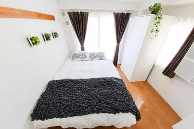a bedroom with a bed with a black blanket at \u30cf\u30a4\u30af\u30ec\u30b9\u30c8\u4e2d\u91ce103 in Tokyo