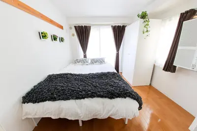 a bedroom with a bed with a black blanket at \u30cf\u30a4\u30af\u30ec\u30b9\u30c8\u4e2d\u91ce103 in Tokyo