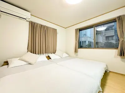 two beds in a room with a window at Shinjuku Cozy Loft, 2BR, 3DoubleBeds&Living in Tokyo