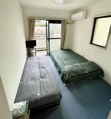 a bedroom with two beds in a room with a window at Tokyo Shinjuku Goose Goose Apart in Tokyo