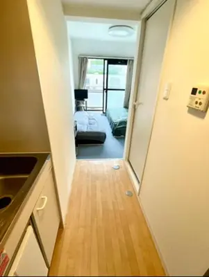 a hallway with a door leading to a room with a bed at Tokyo Shinjuku Goose Goose Apart in Tokyo