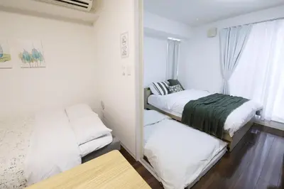 a bedroom with two beds and a mirror at Guest House KAMEARI 203 in Tokyo