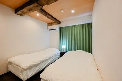 two beds in a room with a green curtain at Seed INN Iori-\u5eb5- in Tokyo