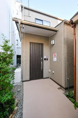 a building with a brown door and a sidewalk at Seed INN Iori-\u5eb5- in Tokyo