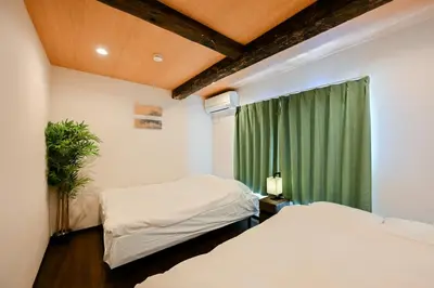 two beds in a room with a green curtain at Seed INN Iori-\u5eb5- in Tokyo