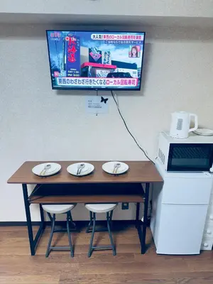 a table with two chairs and a monitor on a wall at \u6a31\u82b1\u5bbf\u6d89\u8c37\u7ad9\u5f92\u6b654\u5206\u949f in Tokyo