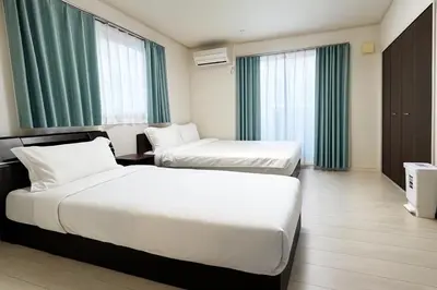 two beds in a hotel room with green curtains at Retreat BABA in Tokyo
