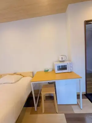 a room with a bed and a table with a microwave at Silvership Hotel 502 in Tokyo