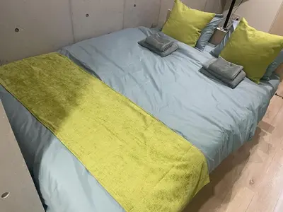 a large bed with a yellow blanket and pillows at Green Apple Otsuka 201 in JR Otsuka station in Tokyo