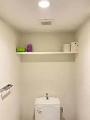 a bathroom with a toilet with shelves on the wall at Artessimo\u62bc\u4e0a 401 in Tokyo