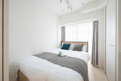 a white bedroom with a bed with a window at \u30eb\u30cd\u30b5\u30f3\u30b9\u30b3\u30fc\u30c8\u672c\u6240\u543e\u59bb\u6a4b in Tokyo