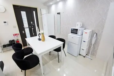 a kitchen with a white table and black chairs at \u738b\u5b50\u795e\u8c37\u5e73\u5c4b in Tokyo