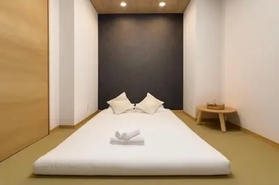 a large white bed in a room with a table at Silvership Hotel 101 in Tokyo