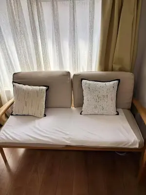 a couch with two pillows sitting in front of a window at \u9e1f\u8d8a201\u6210\u7530\u7fbd\u7530\u673a\u573a\u53ef\u76f4\u8fbe\u4ea4\u901a\u4fbf\u5229\u5e02\u4e2d\u5fc3 in Tokyo