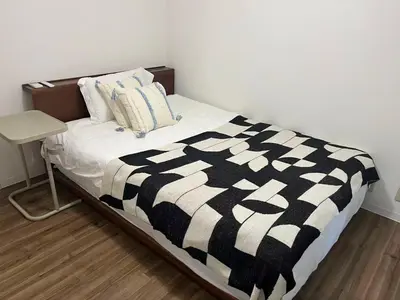 a bed with a black and white blanket and a table at \u9e1f\u8d8a202\u6210\u7530\u7fbd\u7530\u673a\u573a\u76f4\u8fbe\u6b65\u884c8\u5206\u949f\u53ef\u62b5\u8fbe\u6c11\u5bbf\u4f4d\u7f6e\u4f18\u8d8a in Tokyo