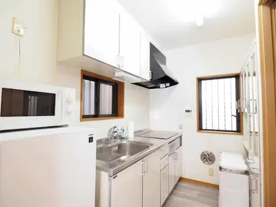 a white kitchen with a sink and a microwave at Haku Nest Ichinoe in Tokyo