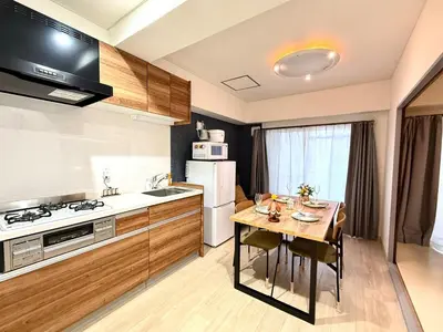 a kitchen with a table and a stove and a refrigerator at Moto Sakura 403,2 bedrooms with 4 beds, 6 people, direct access to Narita and Haneda Airports, Asakusa and Ueno area, 5 train lines available, Bicycles free rental in Tokyo