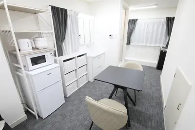 a small white kitchen with a table and chairs at Shinbashi Oliver in Tokyo