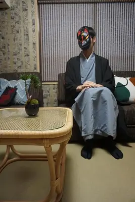 a man wearing a mask sitting on the floor next to a table at WA NO YADO-Asakusa Retreat 10 min walk from Asakusa Designer curated stylish room 3 in Tokyo