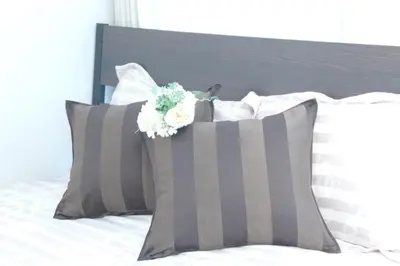 a bed with gray and white pillows and flowers on it at #3 Tokyo Shinjuku Shibuya room in Tokyo