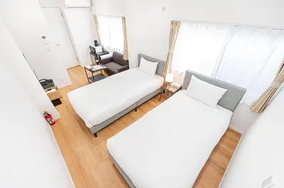 two beds in a small room with a couch at \u83ca\u5ddd\u99c5\u5f92\u6b69\u516d\u5206 Zaito Kiku House in Tokyo