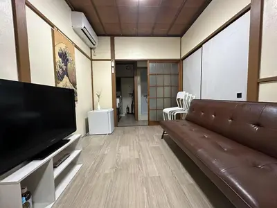 a living room with a couch and a flat screen tv at \u6d45\u8349 \u30b9\u30ab\u30a4\u30c4\u30ea\u30fc\u570f10\u5206 \u4ea4\u901a\u81f3\u4fbf \u6d45\u8349\u5bfa\u89b3\u5149 \u53cc\u9b5a\u306e\u5bbf \u6771\u5411\u5cf65 in Tokyo