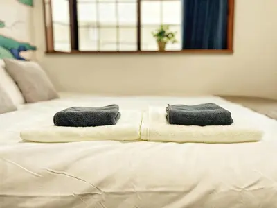 a bed with two towels sitting on top of it at KYM Heights in Tokyo