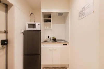 a small kitchen with a black refrigerator and a microwave at Cheerful Kanegafuchi in Tokyo