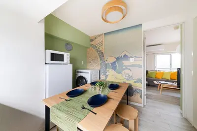 a kitchen with a wooden table and a refrigerator at Cheerful Takadanobaba in Tokyo